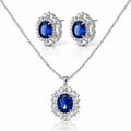 Silver-tone jewelry set featuring a necklace and matching stud earrings with oval deep blue gemstones surrounded by clear crystal halo settings, on a white background.