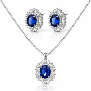 Silver-tone jewelry set featuring a necklace and matching stud earrings with oval deep blue gemstones surrounded by clear crystal halo settings, on a white background.