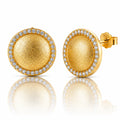 A pair of gold dome stud earrings with a halo of small clear stones, shown on a white background with a soft reflection below. One earring is facing forward, showing the textured gold center and the side post with a '925' sterling silver mark, while the other is turned sideways.