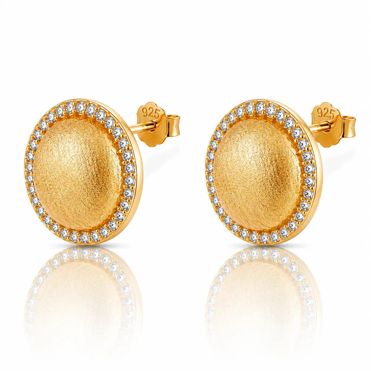 A pair of round gold stud earrings with a textured center and a border of small clear stones, shown on a white background with a soft reflection below.