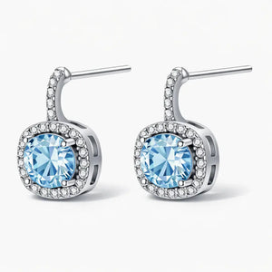 Silver drop earrings with round blue gemstones and pavé clear crystals on white background