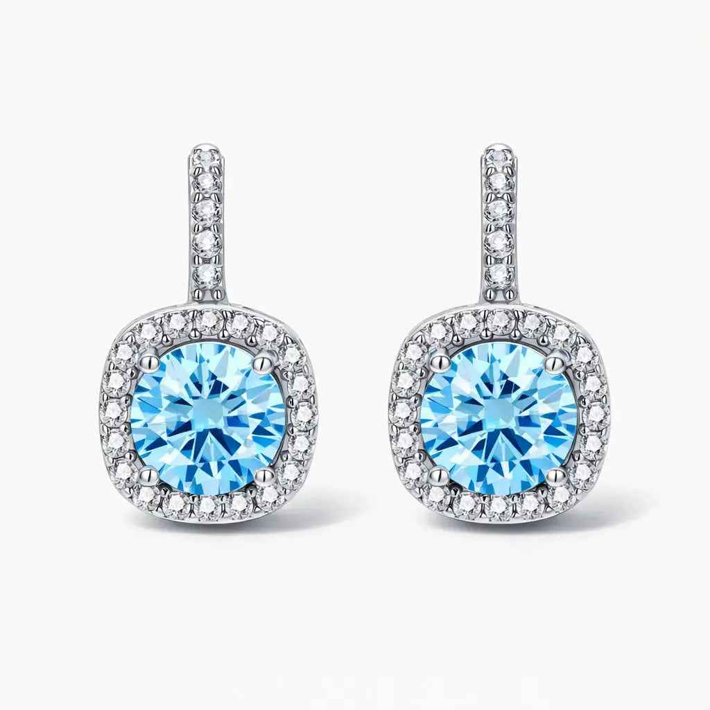 Elegant silver drop earrings with round blue gemstones and pavé clear stones on a white background