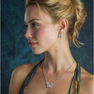 Woman wearing butterfly pendant necklace and blue gemstone drop earring, elegant jewelry