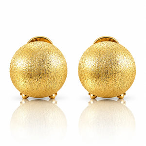 A pair of textured gold spherical stud earrings with small gold feet, displayed on a clean white reflective surface.