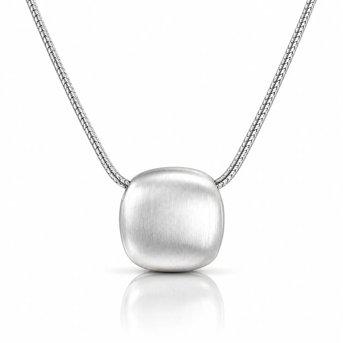 A silver pendant necklace featuring a brushed, rounded square pendant suspended from a delicate silver chain, set against a clean white background with a soft reflection below.