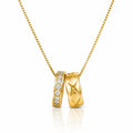 A gold pendant necklace featuring two interlocking bands: one with a row of clear stones and the other with an X-shaped cutout pattern, suspended on a gold chain against a white background.