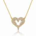 A gold heart-shaped pendant necklace paved with small clear stones, suspended from a delicate gold chain on a white background with a soft reflection below.