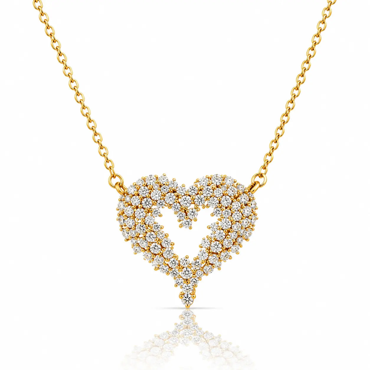 A gold heart-shaped pendant necklace paved with small clear stones, suspended from a delicate gold chain on a white background with a soft reflection below.
