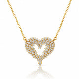 A gold heart-shaped pendant necklace paved with small clear stones, suspended from a delicate gold chain on a white background with a soft reflection below.