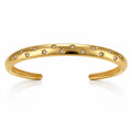 A polished gold open cuff bracelet decorated with small star-shaped settings holding clear round stones, shown on a clean white background with a soft reflection below.