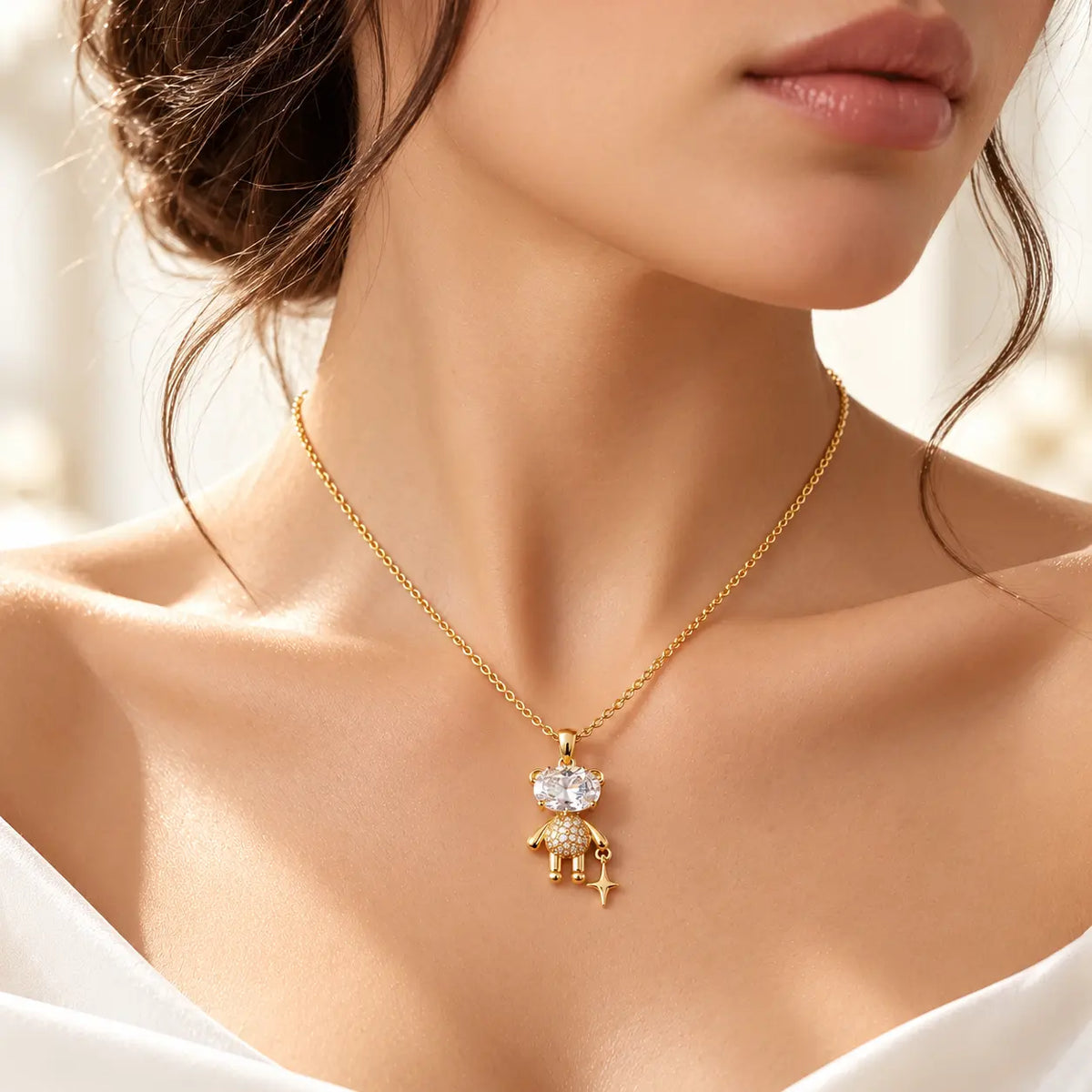 A close-up lifestyle shot of a model wearing a delicate gold pendant necklace. The pendant features a small gold figure adorned with clear crystals, which are excluded from the color analysis according to the rules.