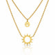 A double-layered gold necklace set featuring a delicate cable chain with a small smiley face disc pendant and a thicker link chain with a sunburst pendant, displayed on a clean white background with a soft reflection.