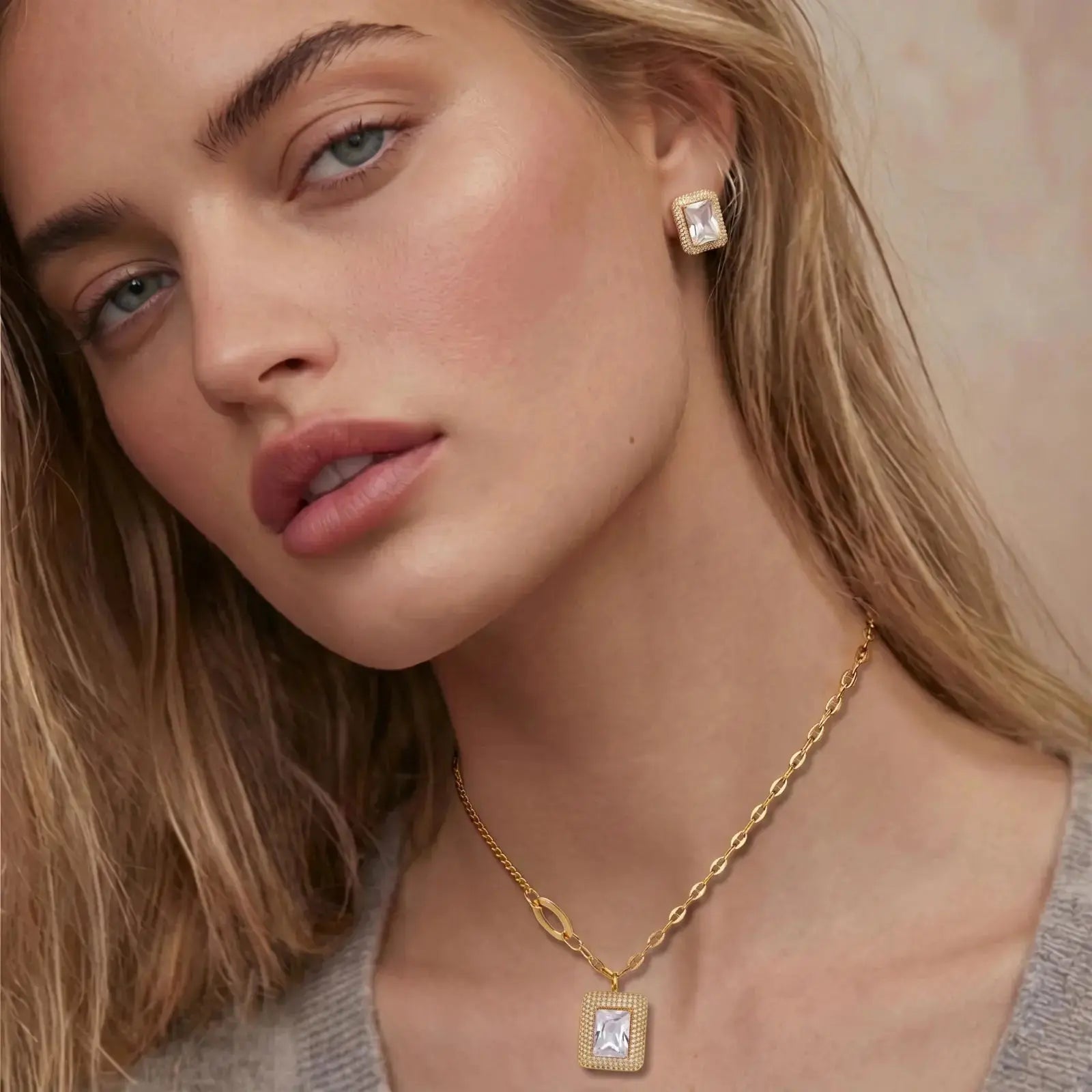 Close-up of a woman wearing gold jewelry with a neutral background
