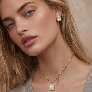 Close-up of a woman wearing gold jewelry with a neutral background