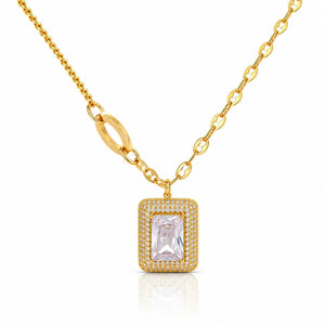 A gold chain necklace with a rectangular pendant featuring a clear baguette-cut center stone surrounded by a halo of small clear stones, set against a plain white background.