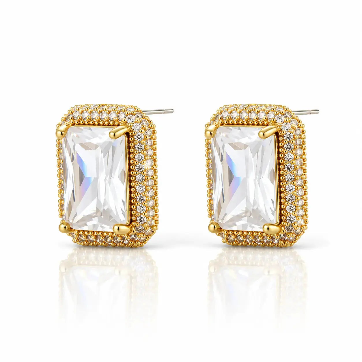 A pair of gold-plated rectangular stud earrings featuring a large clear emerald-cut center stone surrounded by a halo of small clear stones, set against a clean white background with a soft reflection.