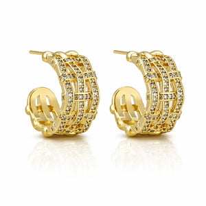A pair of gold huggie hoop earrings adorned with multiple rows of clear pavé-set cubic zirconia stones, displayed on a clean white background with a soft reflection.