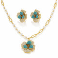 Gold-tone jewelry set with a pearl-and-link chain necklace, matching stud earrings, and a flower-shaped pendant. The flowers are accented with turquoise blue stones and pavé-set clear stones on a white background.