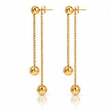 A pair of gold dangle earrings with spherical beads, shown on a clean white background with a subtle reflection below.