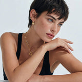 Woman wearing gold jewelry with a neutral background