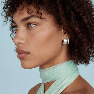 Close-up of a person wearing a light green scarf with a plain background