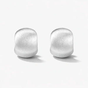 Matte silver curved stud earrings on white background, minimalist modern jewelry