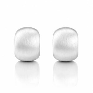 A pair of matte-finished silver stud earrings with a rounded rectangular shape, displayed on a clean white background with soft reflections below.