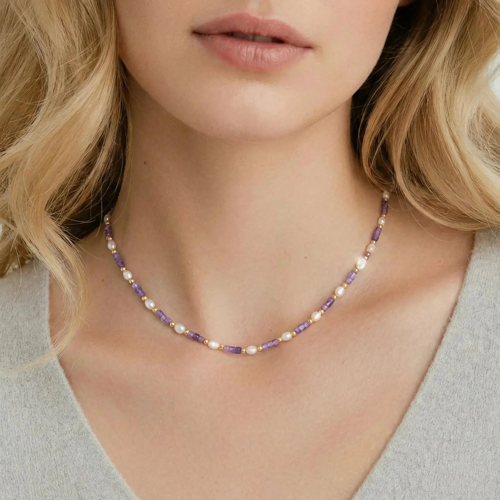 Woman wearing a delicate violet and pearl beaded necklace on bare neck