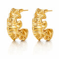 A pair of gold huggie hoop earrings with a textured, organic wavy surface, displayed on a clean white background with a soft reflection below.