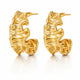 A pair of gold huggie hoop earrings with a textured, organic wavy surface, displayed on a clean white background with a soft reflection below.