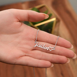 Close-up of custom name necklace with heart detail held in hand