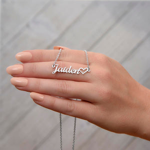 Close-up of custom name necklace with heart detail held in hand