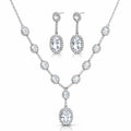 A silver-tone jewelry set featuring a V-shaped necklace and matching drop earrings, both adorned with clear round and oval gemstones, shown on a plain white background.