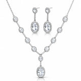 A silver-tone jewelry set featuring a V-shaped necklace and matching drop earrings, both adorned with clear round and oval gemstones, shown on a plain white background.
