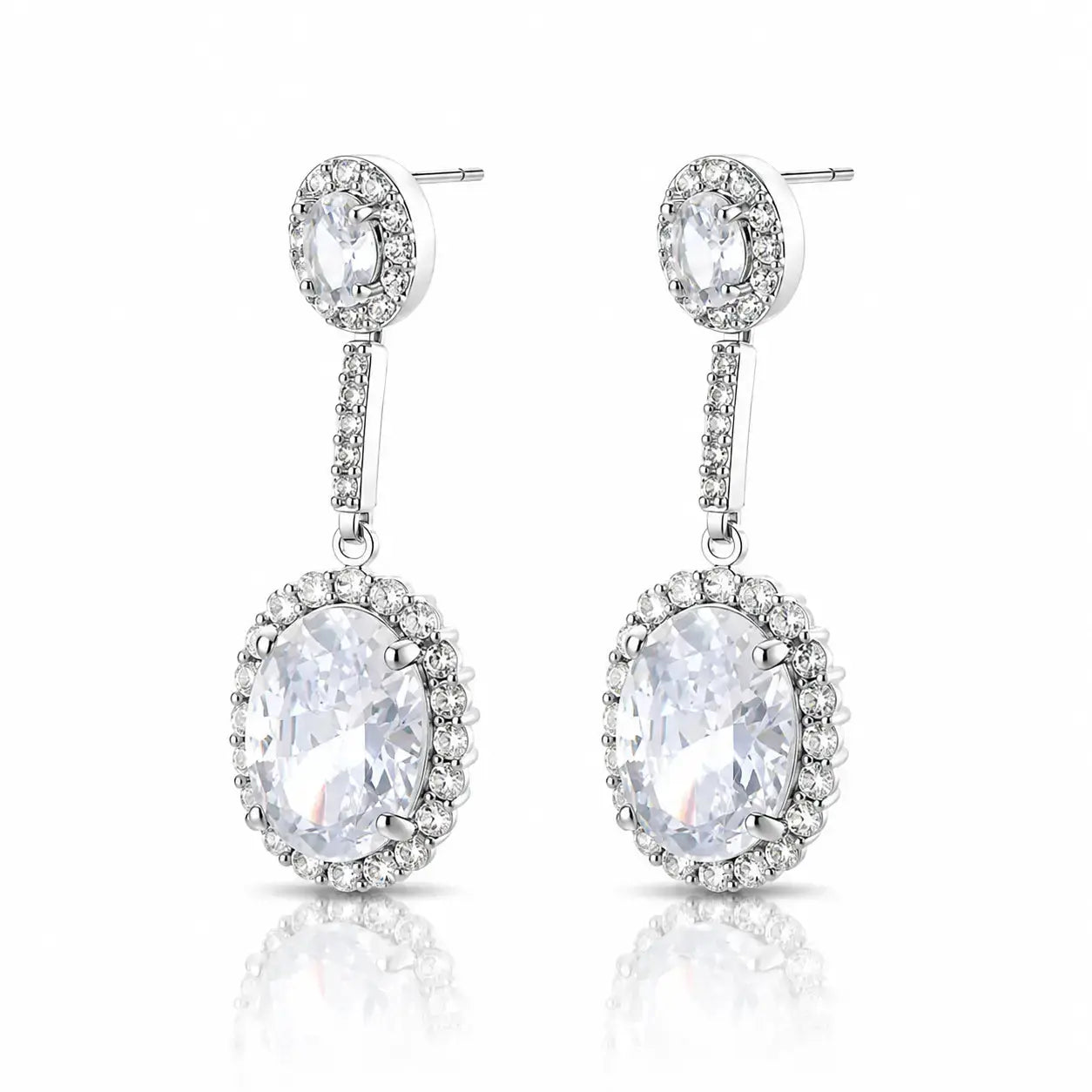 A pair of silver-tone drop earrings with oval clear gemstones surrounded by small accent stones, shown on a white background with a soft reflection below.