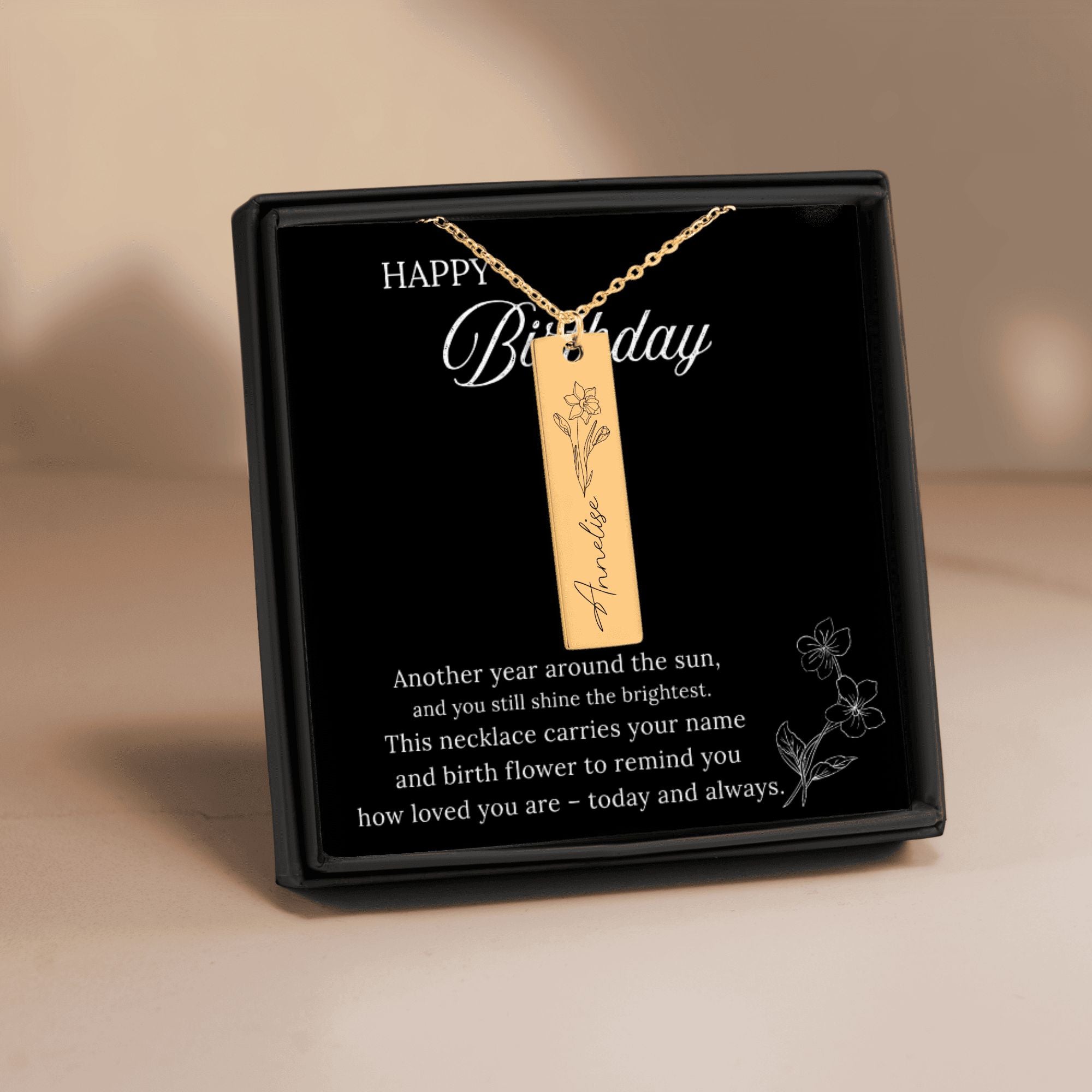 Gold necklace with a pendant in a black gift box on a beige background