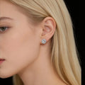 Close-up of a blonde woman wearing a sparkling silver stud earring against black background
