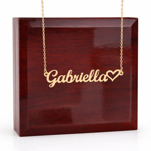 Gold necklace with 'Gabriella' and a heart pendant on a wooden box