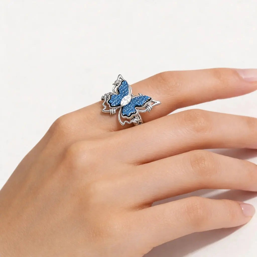 Silver butterfly ring with blue gemstones on woman's hand, luxury-inspired jewelry