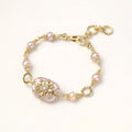 Gold bracelet with pink pearls on a white background