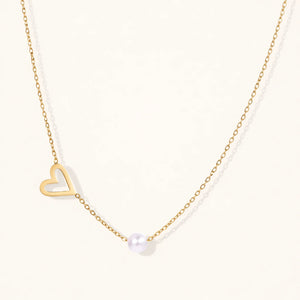 Gold necklace with a heart pendant and pearl on a white background