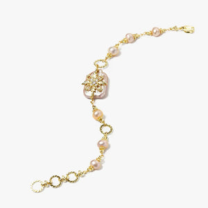 Gold bracelet with pink pearls and floral centerpiece on white background
