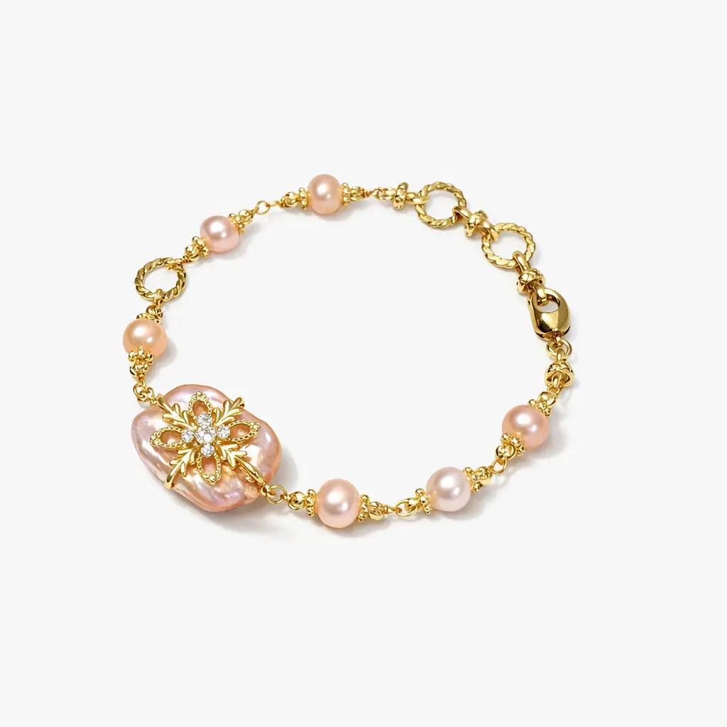 Gold floral bracelet with pink pearls and crystal accents on white background