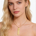 Woman wearing a gold necklace with a pendant on a white background