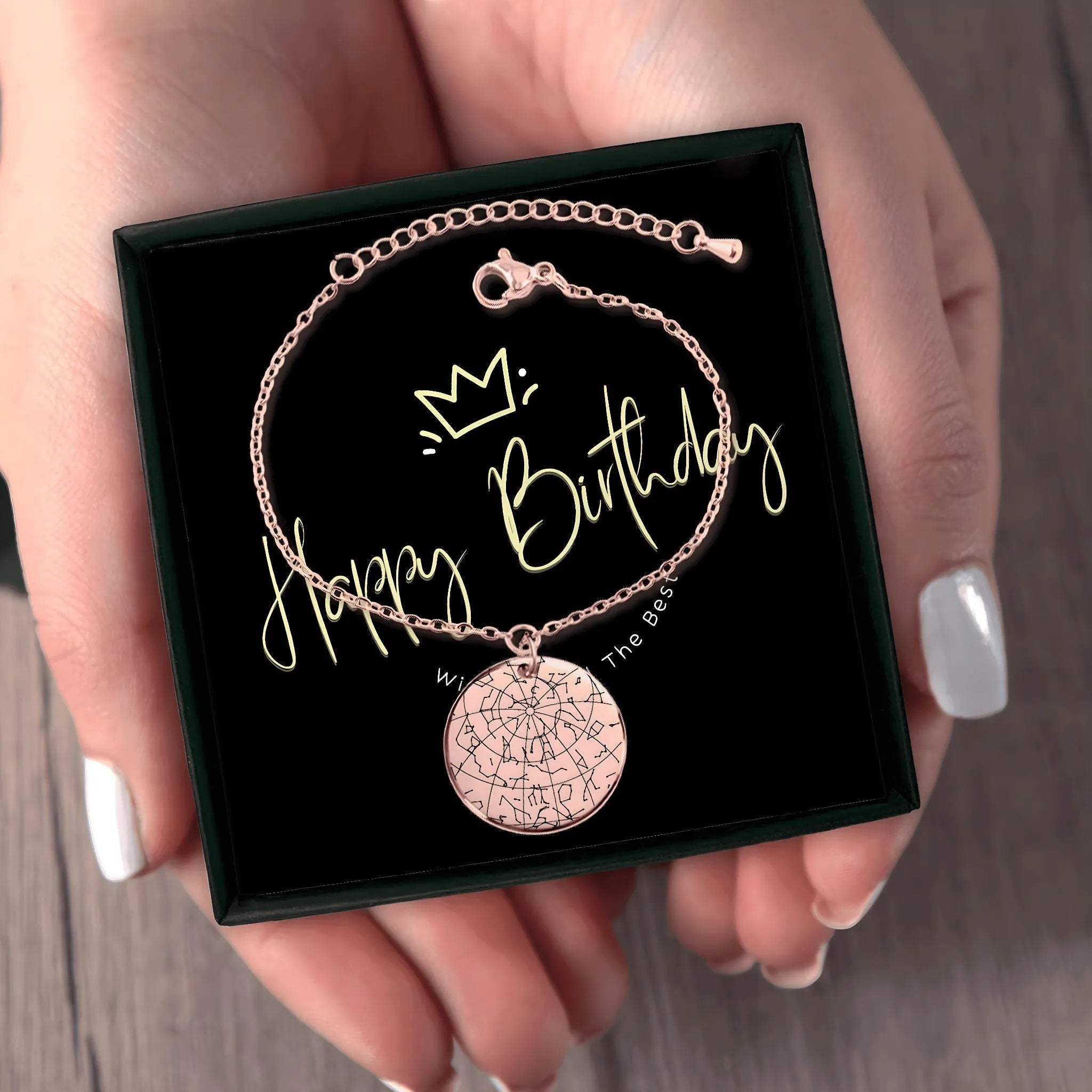 Rose gold star map bracelet in black gift box with 'Happy Birthday' message, held by hands