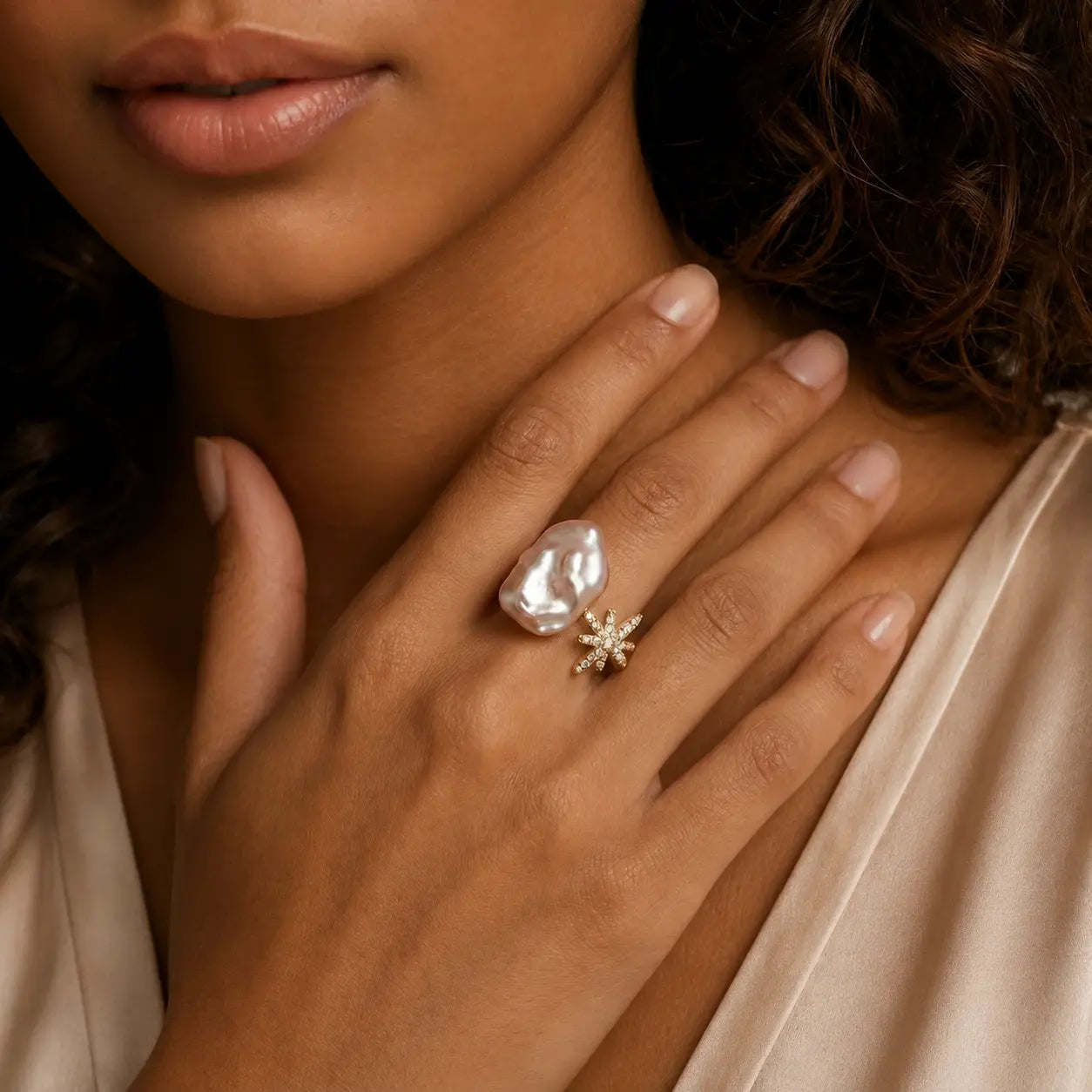 Close-up of a woman's hand wearing two rings with a soft focus on her face.