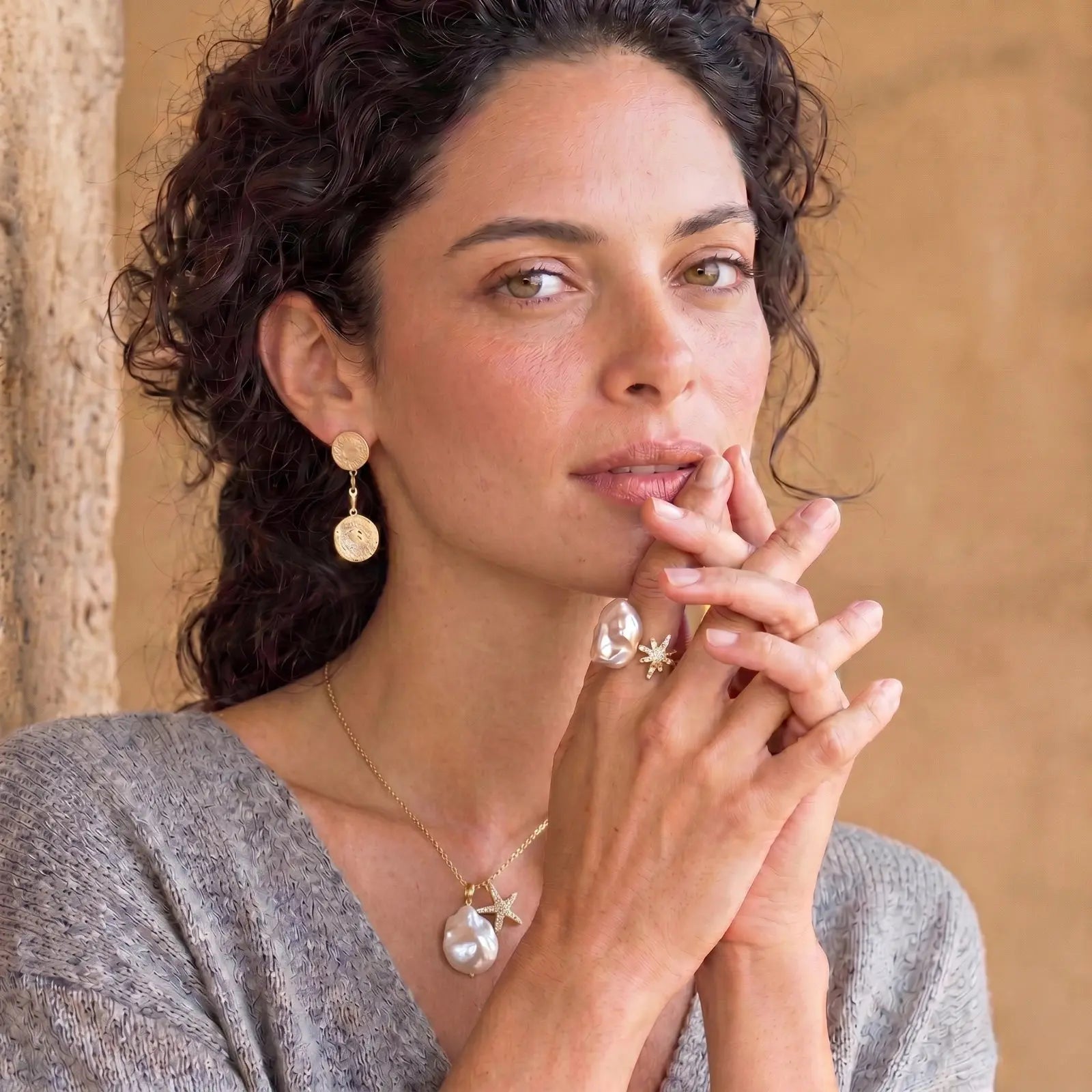 Woman with jewelry including earrings and a necklace, with a neutral background